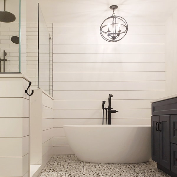 Modern bathtub and light with shiplap wall behind
