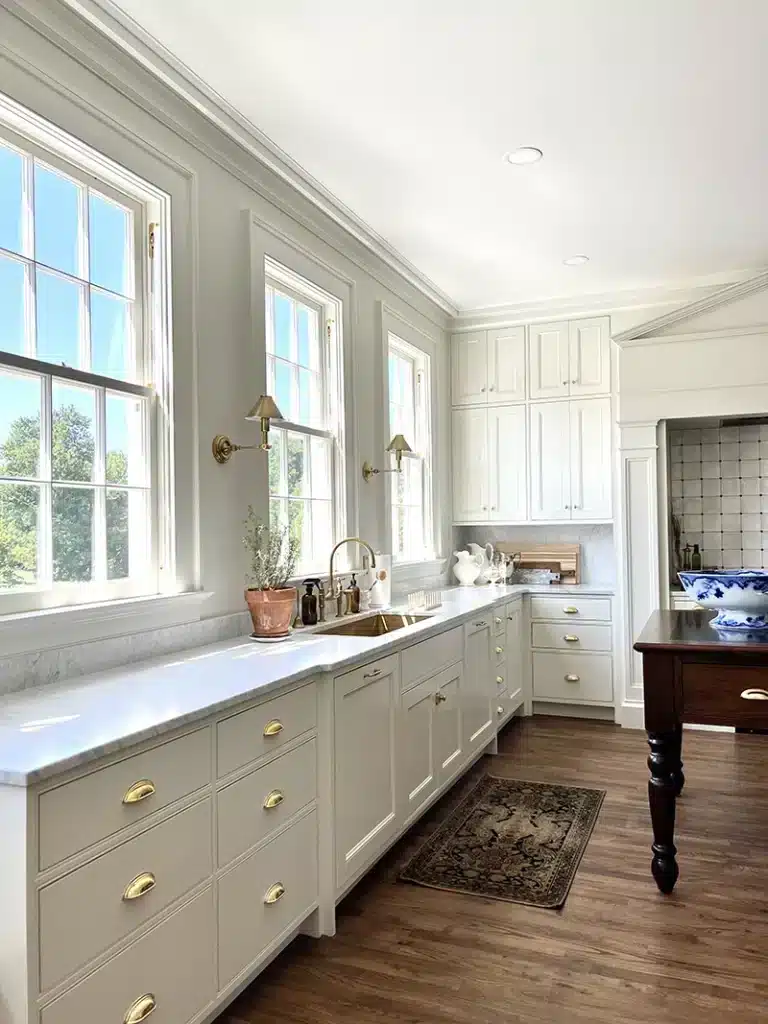 Beaded kitchen cabinets with brass hardware matching beaded casing around windows