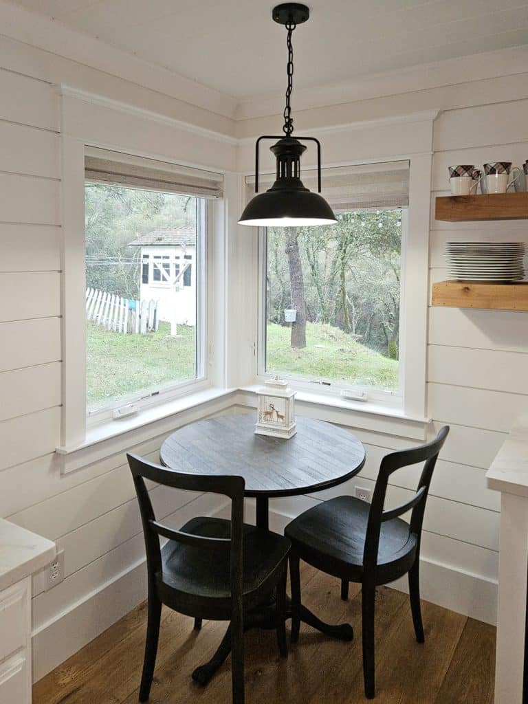 Corner kitchen nook, black wood table and chairs. Double window in corner, Classical Craftsman casing and shiplap walls