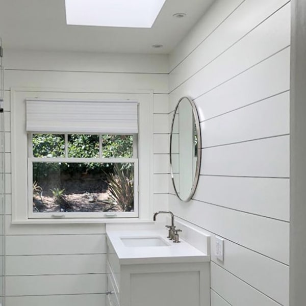 Shiplap walls in bathroom with circular mirror above sink and S4S picture frame window casing