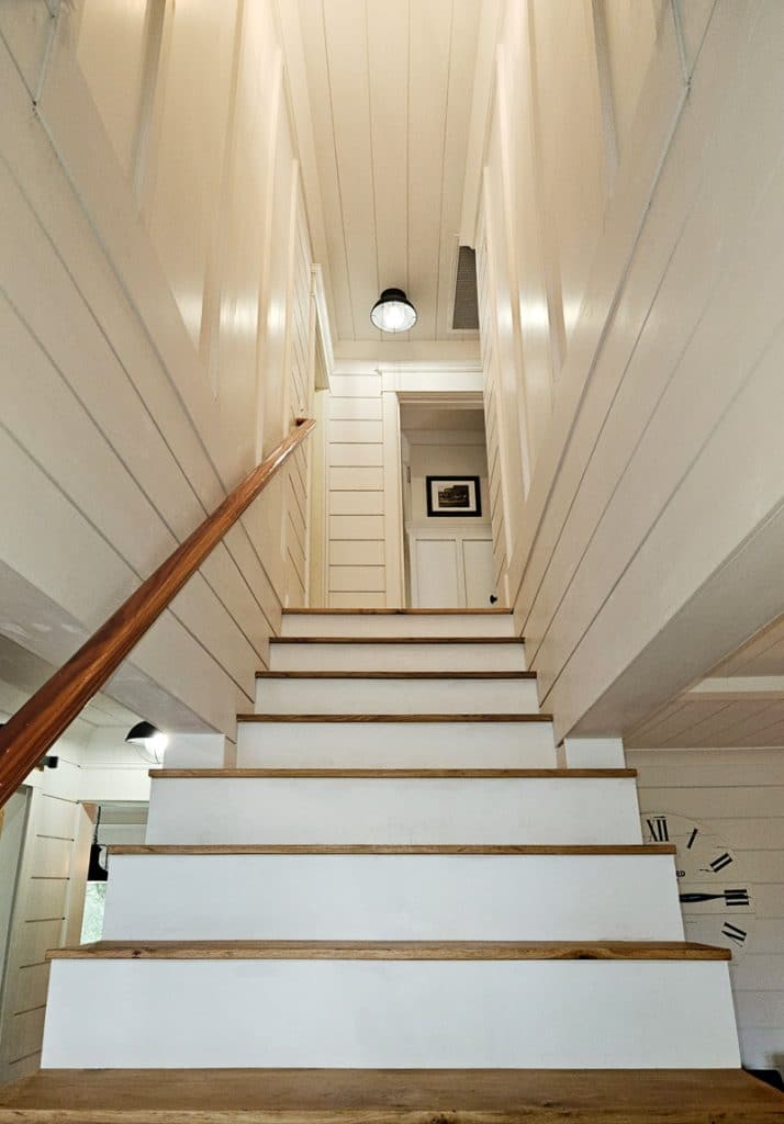 Looking up stairs at risers with stain grade steps and shiplap walls