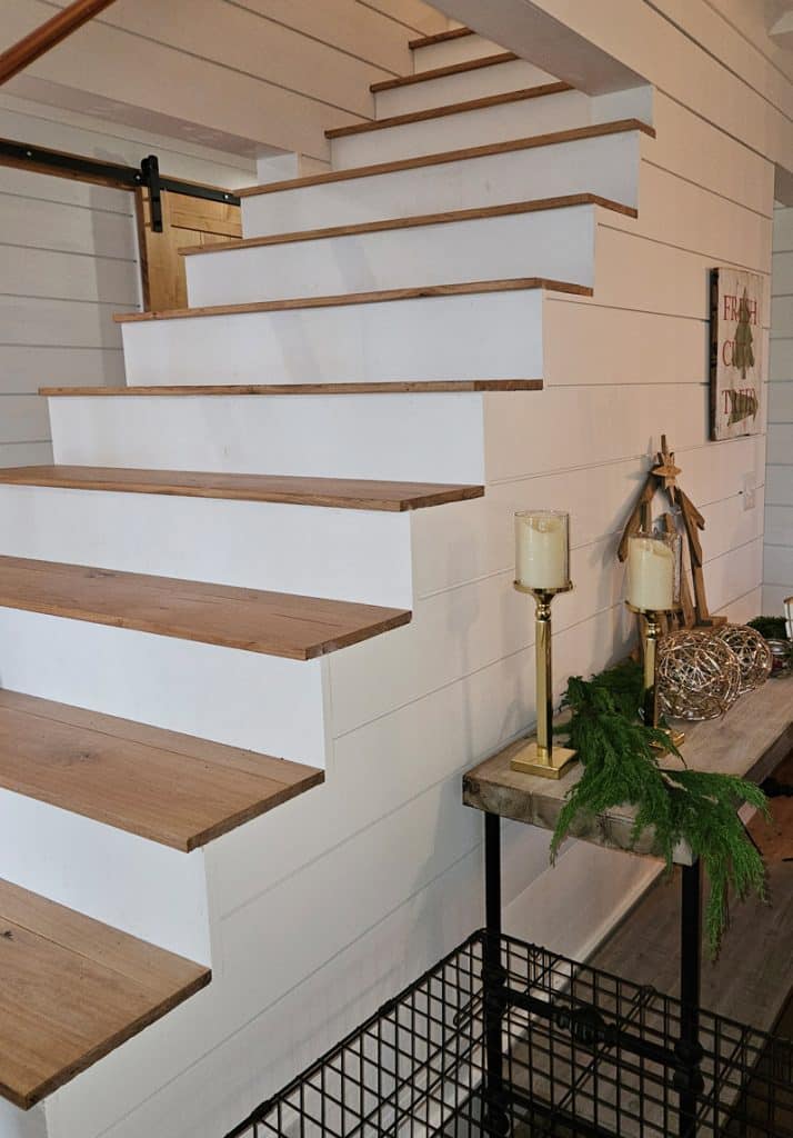 Side view of stairs with white risers and stain grade steps with shiplap walls on the side