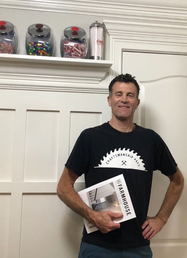 Steve standing in front of wainscoting holding a Farmhouse Idea Book