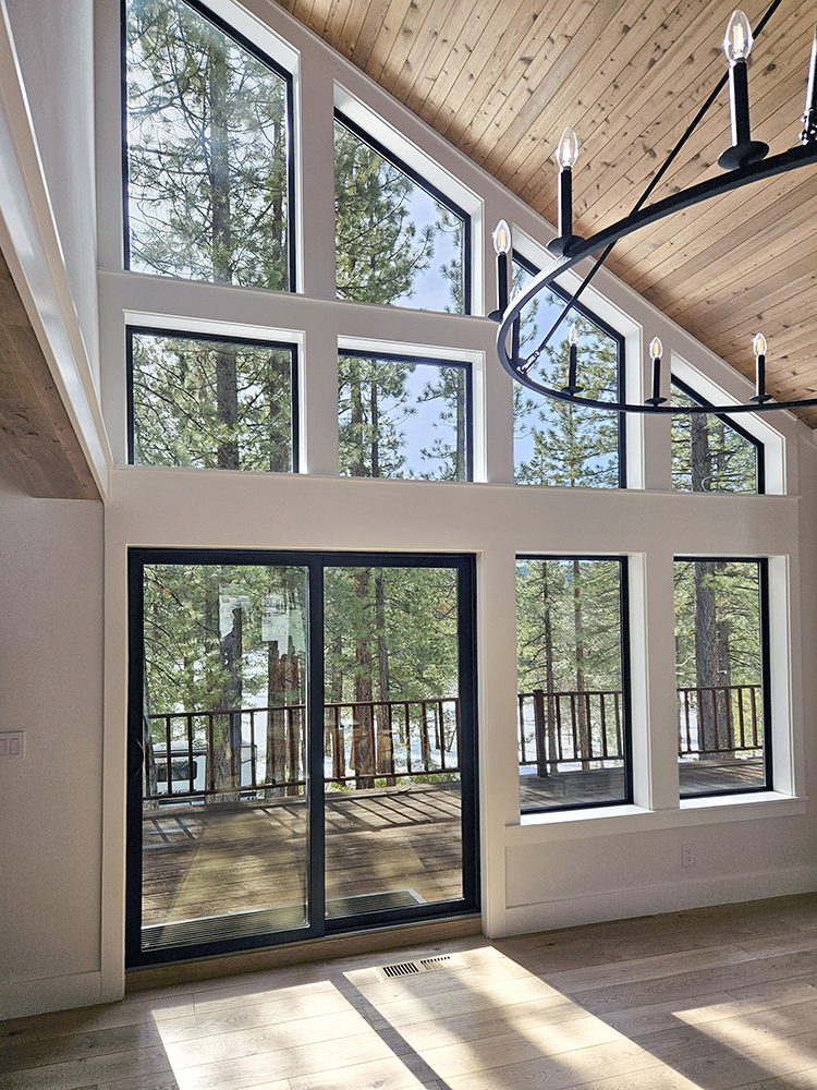 Huge wall of windows in the great room looking on to forest outside