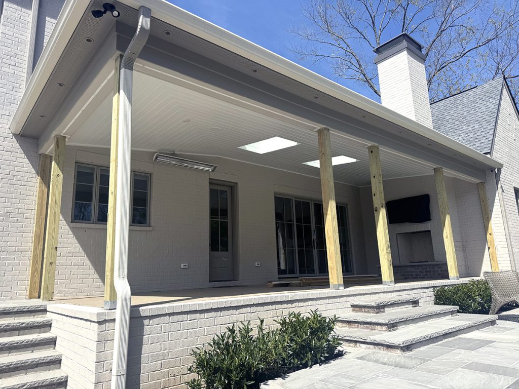 Porch of a tan brick house, unfinished columns, v-groove porch lid exterior ceiling