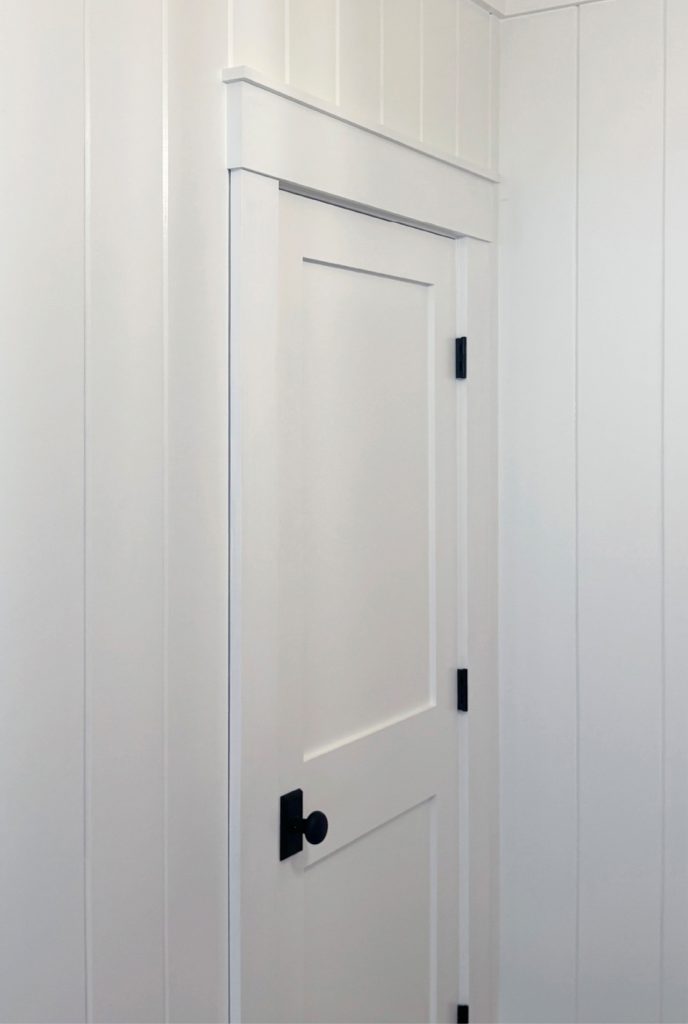 corner closet with streamlined craftsman trim and vgroove walls, shaker farmhouse door