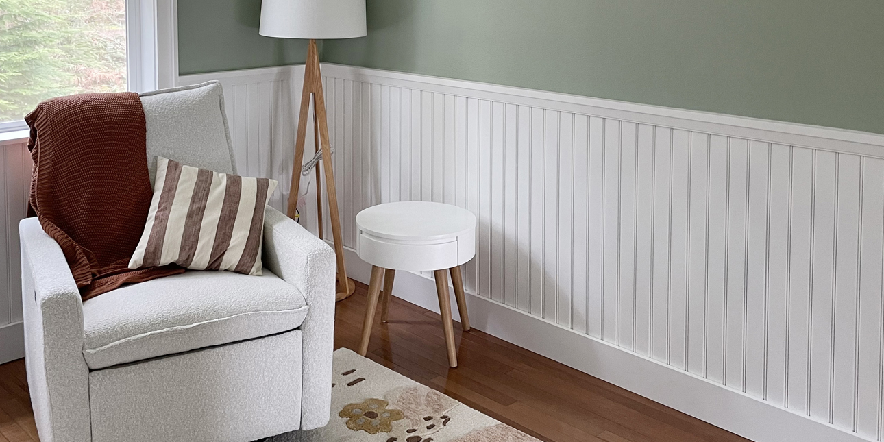Babys nursery with white beadboard wainscoting, white chair, green wall