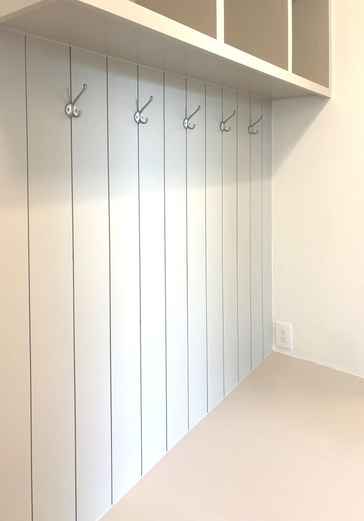 Custom mudroom storage with vertical shiplap and hooks