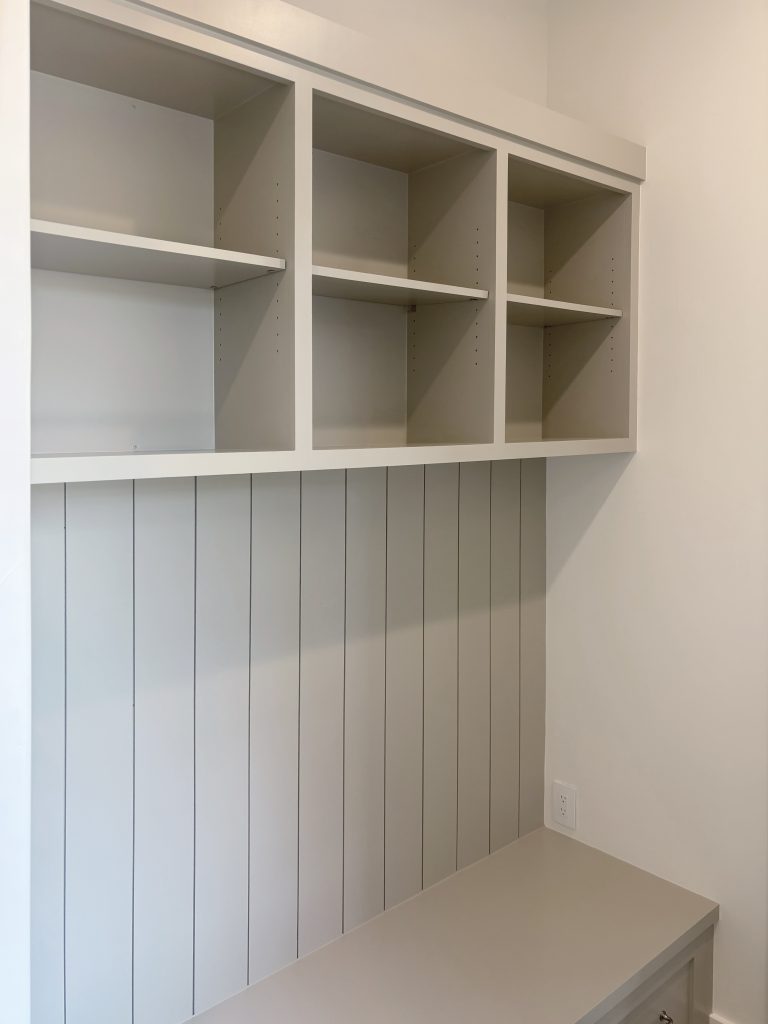 Custom mudroom built-ins with vertical shiplap and shelving above