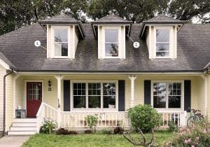 Front view of yellow house before image with callouts for where the dormers are to be improved.